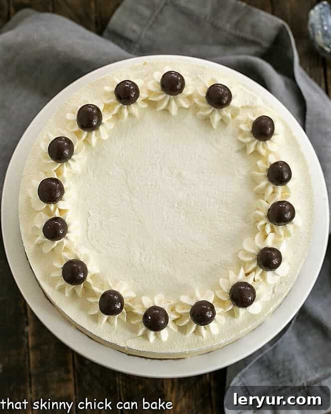 Tiramisu cheesecake - with coffee soaked ladyfingers, coffee flavored cheesecake and a luscious mascarpone topping, this is one dreamy layered dessert! Overhead view of a perfectly sliced Tiramisu Cheesecake on a white cake stand, dusted with cocoa powder.