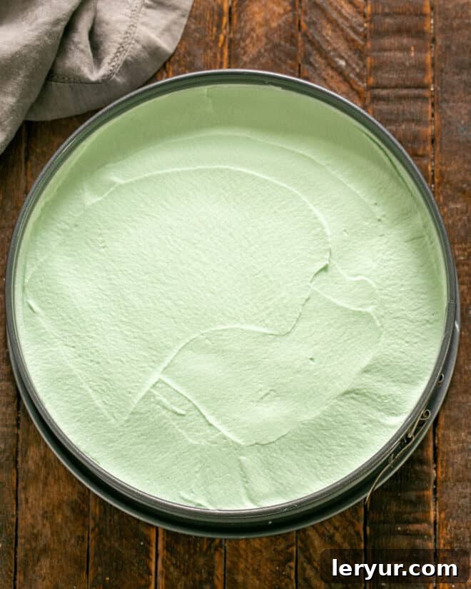 Emerald Oasis Oreo Dream 7 Step-by-step image of whipped cream being folded into the mint mixture before being poured over the crust and frozen.