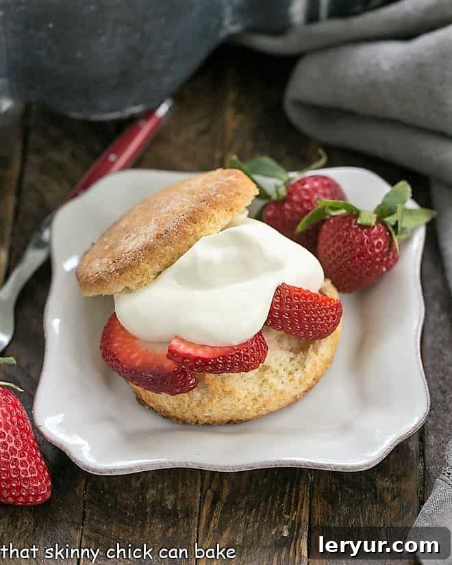 Two Strawberry Shortcakes with White Chocolate Whipped Cream on a square white plate, with fresh mint garnish.