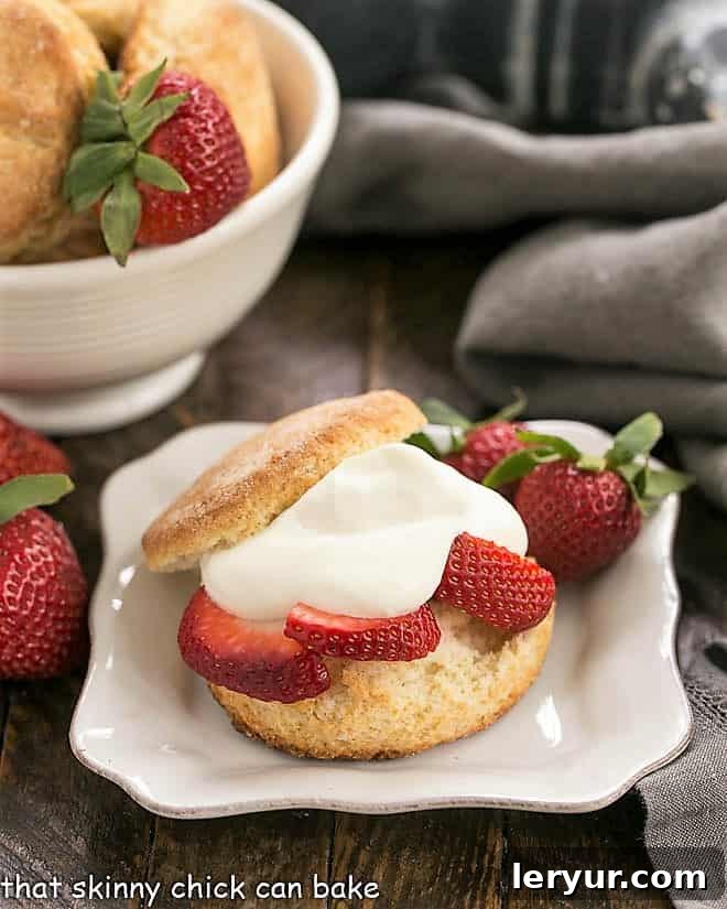 Strawberry Shortcakes with White Chocolate Mousse on a square white plate, with a bowl of biscuits in the background.