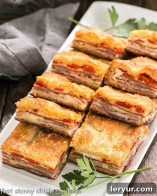 Perfectly cut Antipasto Squares lined up on a rectangular platter, showcasing their vibrant layers.