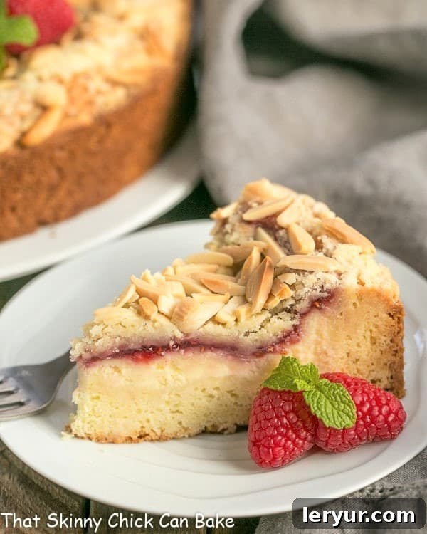 Raspberry Cream Cheese Coffee Cake - Perfect for that special breakfast or brunch! A beautifully sliced Raspberry Cream Cheese Coffee Cake on a small white plate, showing the distinct layers of cake, cream cheese, raspberry jam, and streusel topping.
