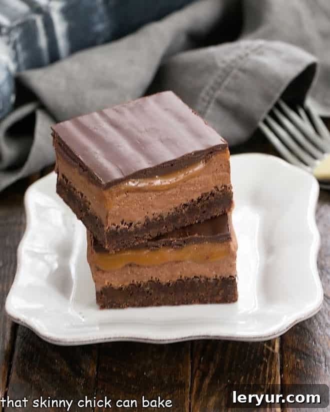 A stack of two luscious Milky Way Brownies on a pristine white plate, showcasing their inviting layers.