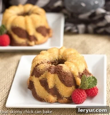 Two mini bundt cakes on square white plates, showcasing their beautiful zebra stripes.