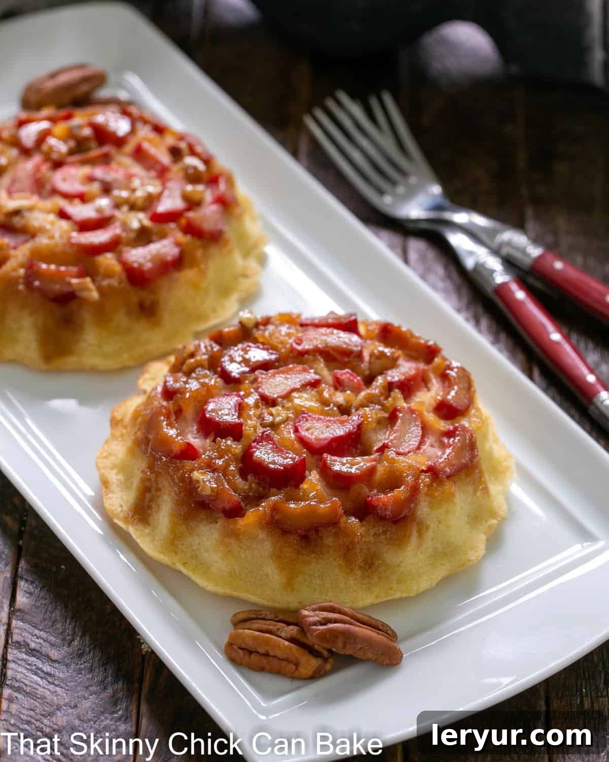 Fresh Rhubarb Upside-down Baby Cakes arranged on a pristine white ceramic tray, showcasing their golden caramel tops and vibrant rhubarb.