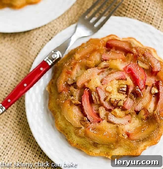 Fresh Rhubarb Upside-down Baby Cake on a white dessert plate with a red handled fork, highlighting the delicious caramel and fruit topping.