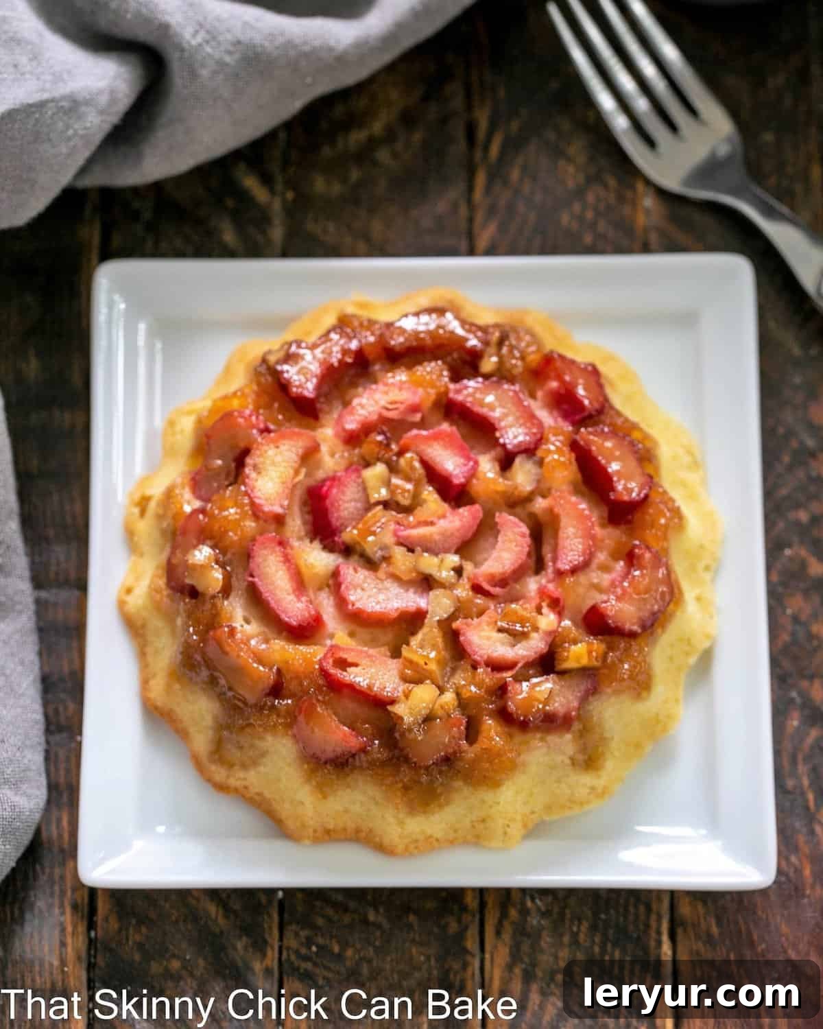 A single, perfectly baked rhubarb baby cake resting on a small, square white plate, ready to be enjoyed.