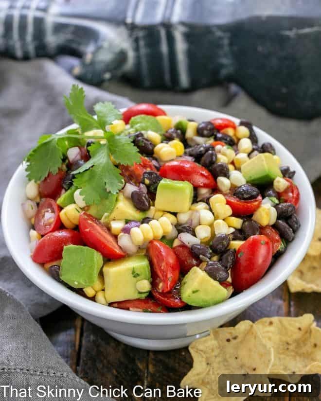 Vibrant Black Bean Avocado Corn Salsa 2 White serving bowl of corn salsa with a few scoops corn chips to the side