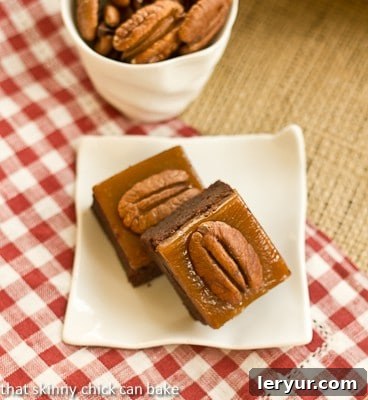 Two turtle brownies on a square white plate on a red and white checked napkin