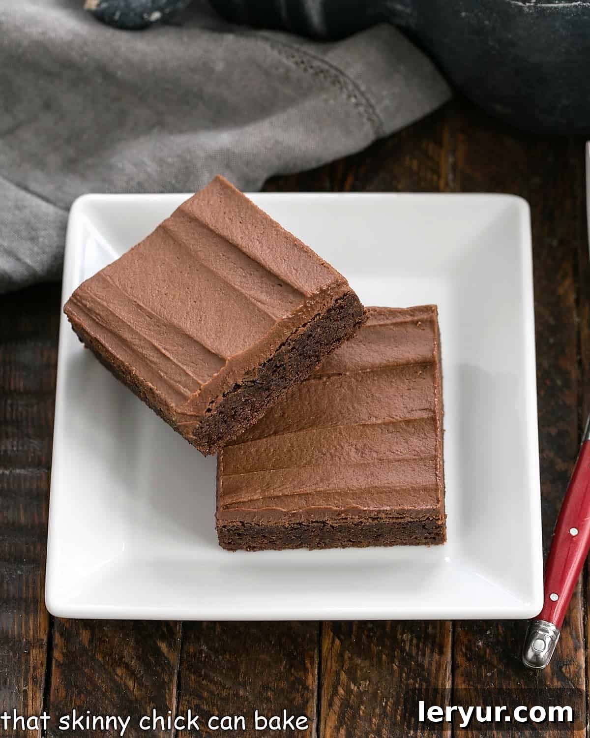2 Rich Frosted Cocoa Brownies on a square white plate, ready to be enjoyed.