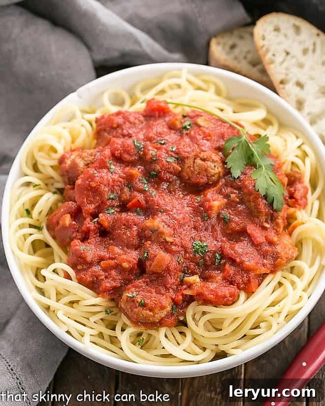 Overhead view of a generous serving of homemade pasta sauce with sausage poured over perfectly cooked spaghetti in a large bowl.