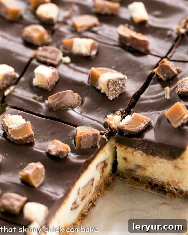 Twix Cheesecake Bars - when two favorite desserts collide! Twix bars, cheesecake plus ganache will dazzle your taste buds!! Close up view of a pan of perfectly sliced Twix Cheesecake Bars, showing the creamy filling and distinct layers.