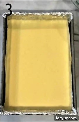 Blackberry Cheesecake Bliss Bars 4 Smooth cheesecake filling evenly spread over the prepared crust in a baking pan, ready for baking.