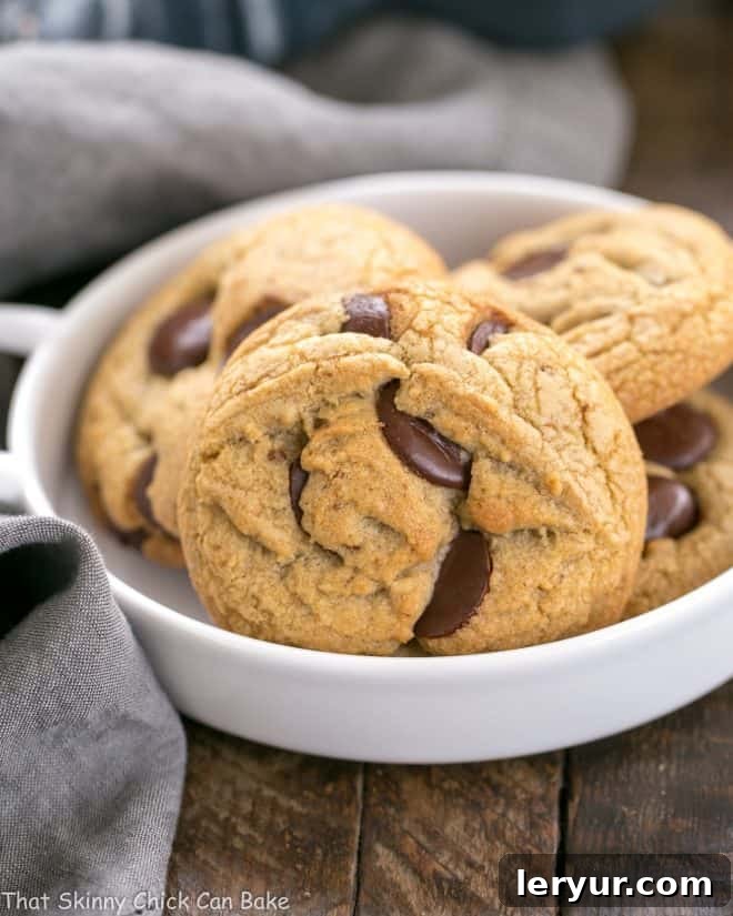 Golden brown butter chocolate chip cookies nestled in a white bowl.