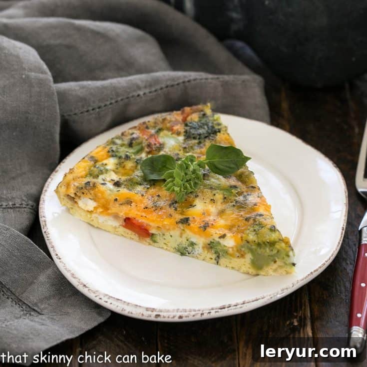 A perfectly cooked slice of Roasted Broccoli Frittata on a white plate, showcasing its golden-brown top and vibrant fillings.