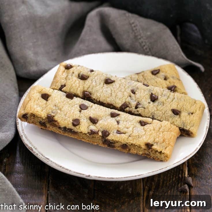 Three perfectly baked chocolate chip cookie sticks resting on a small white plate, ready to be enjoyed.