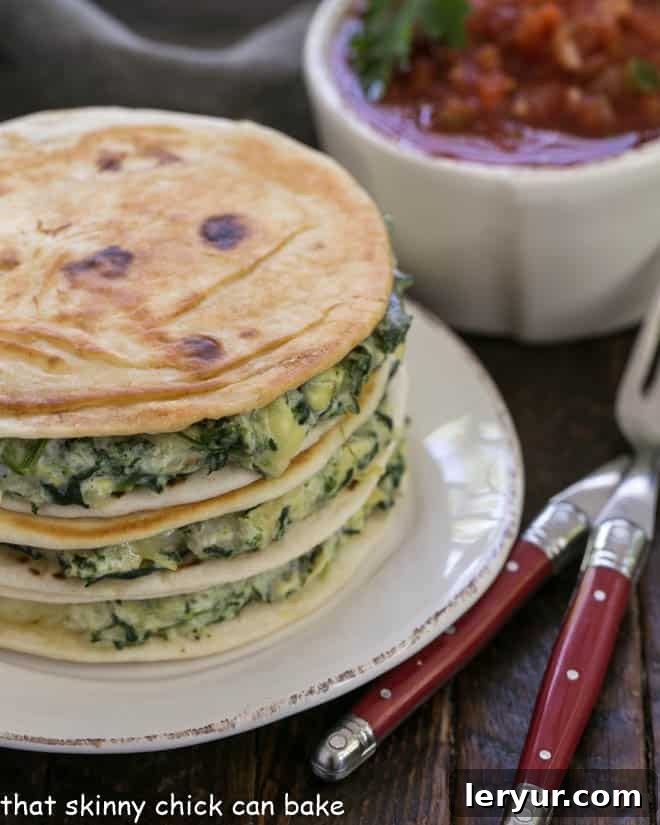 A stack of homemade spinach dip quesadillas on a white plate with red handled forks and a bowl of fresh salsa, emphasizing the cheesy, golden perfection of the tortillas.