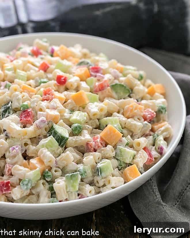 Easy Pasta Salad with Yogurt Dressing - A summer classic with pasta, cheese and vegetables tossed in a mayonnaise and yogurt salad dressing Easy Pasta Salad with Creamy Yogurt Dressing in a white ceramic serving bowl, garnished with fresh herbs.