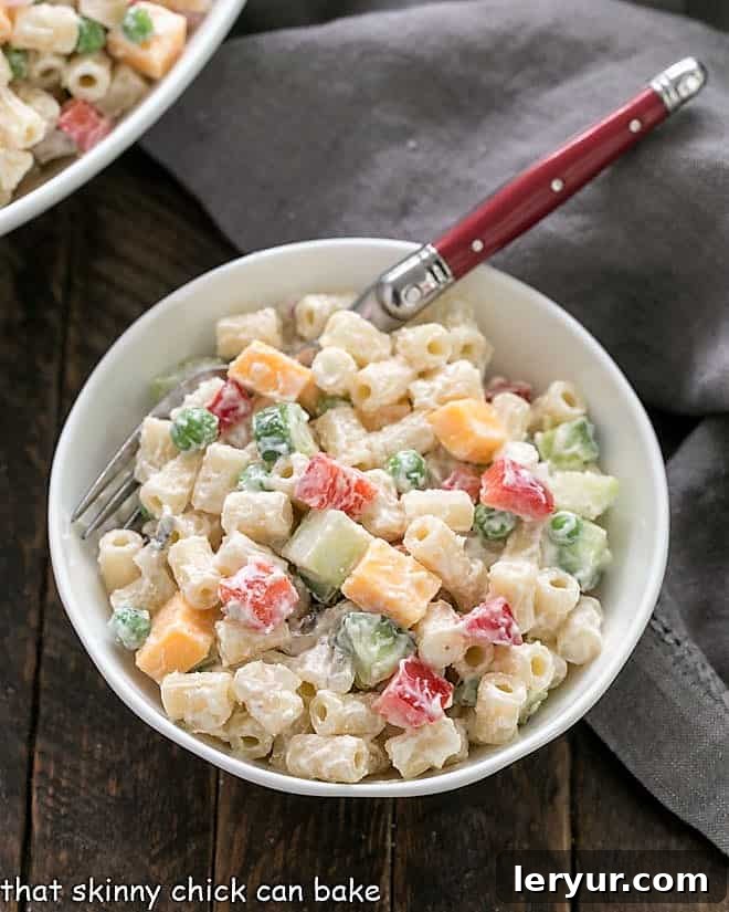 Macaroni Salad Recipe - A summer classic with pasta, cheese and vegetables tossed in a mayonnaise and yogurt salad dressing A close-up view of a small bowl filled with macaroni salad, showcasing the colorful vegetables and creamy dressing.