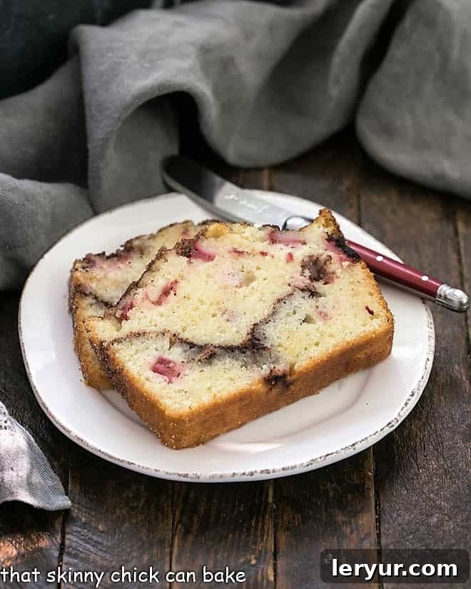 Two perfectly sliced pieces of Cinnamon Swirl Rhubarb Bread on a round white plate, highlighting the delightful cinnamon ribbon.