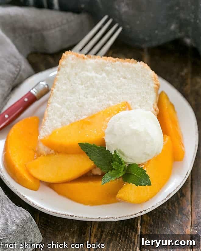 Angel Food Cake from Scratch! Achieve a light, fluffy, and absolutely delicious cake with this best-ever recipe and invaluable tips for new bakers. A delectable slice of Angel Food Cake on a dessert plate, generously topped with fresh peach slices, a swirl of whipped cream, and a garnish of mint, perfect for a summer treat.