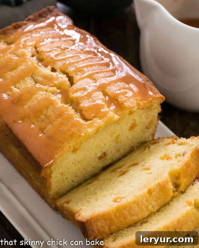 Master the art of summer baking with this Glazed Peach Cake Recipe - a sweet, dense loaf cake filled with succulent diced peaches and crowned with a luscious fresh peach glaze! Pure perfection. A stunning Glazed Peach Pound Cake, artfully sliced and displayed on a white serving tray, ready for an indulgent dessert moment.