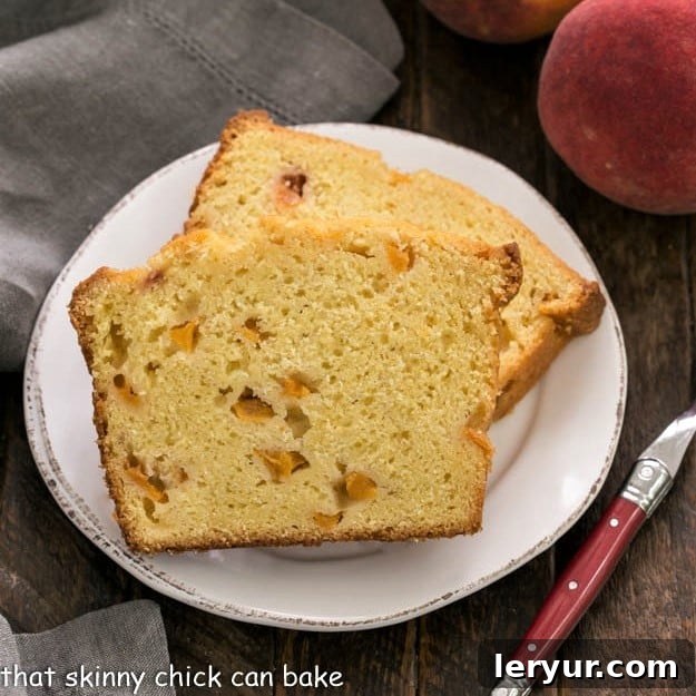 Overhead view of 2 generous slices of Glazed Peach Pound Cake on a white plate, accompanied by a rustic red-handled fork, inviting you to take a bite.