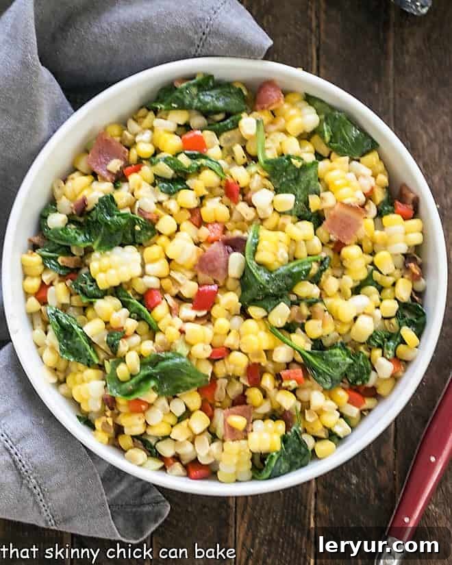 Overhead view of a white serving bowl filled with Skillet Corn with Bacon, Spinach, and Peppers.