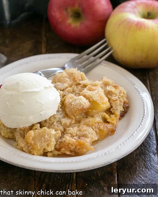 Golden Apple Crumble Served with Velvety Custard 2 Apple crumble on a white plate with a scoop of ice cream.