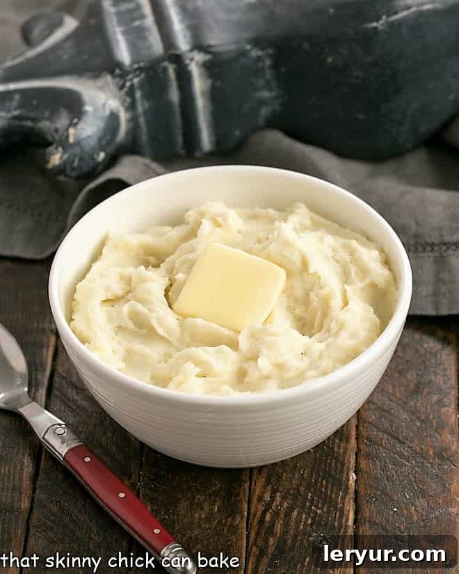 Small bowl of homemade mashed potatoes in a white bowl with a red handled fork