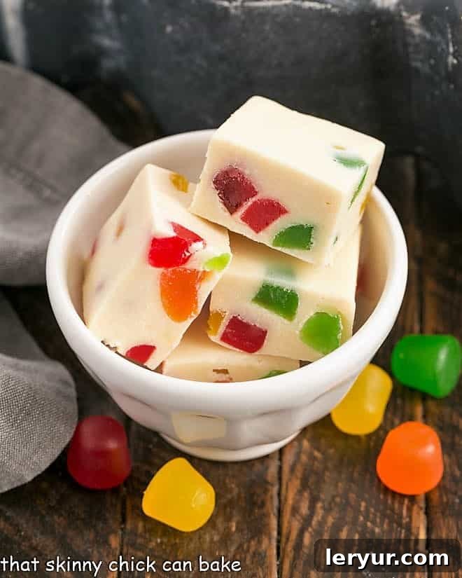 Small white bowl of stained glass white chocolate fudge with gum drops, showing off its inviting texture and colors.