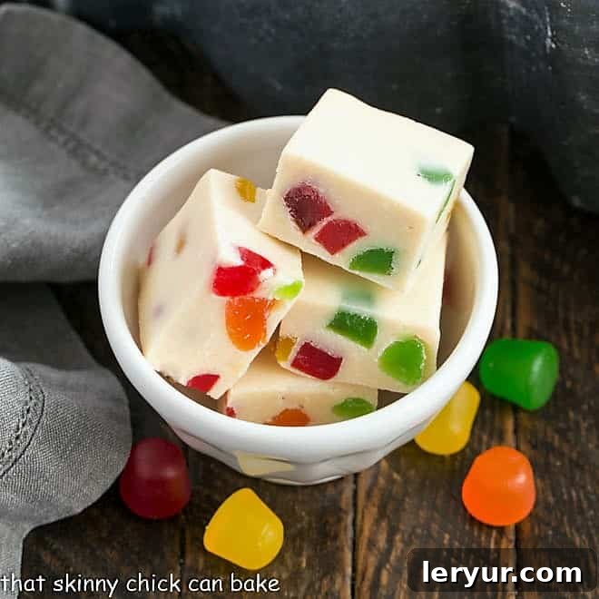 Small white bowl filled with squares of white chocolate fudge, adorned with colorful gumdrops.
