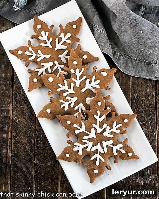 An overhead view of three intricately designed gingerbread snowflakes, highlighting their delicate patterns and golden-brown hue.