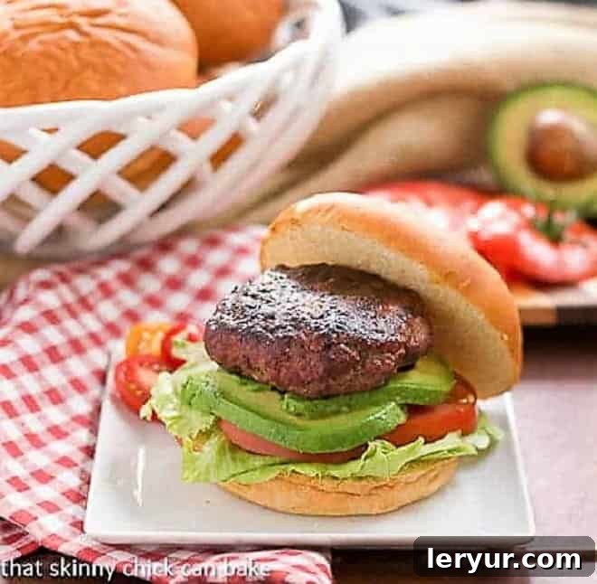 Two California Burgers on a white plate, garnished with lettuce, tomato, and avocado slices.