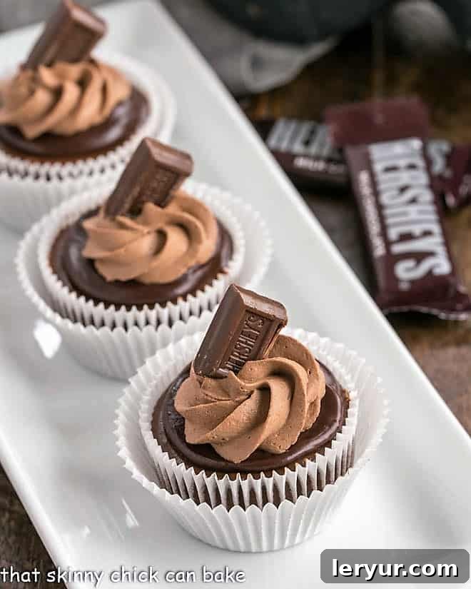 A white serving tray filled with multiple luscious chocolate mini cheesecakes, each topped with a smooth chocolate ganache and a swirl of chocolate whipped cream. These perfectly portioned treats are ready for a party or special gathering, showcasing their elegant presentation and irresistible appeal.
