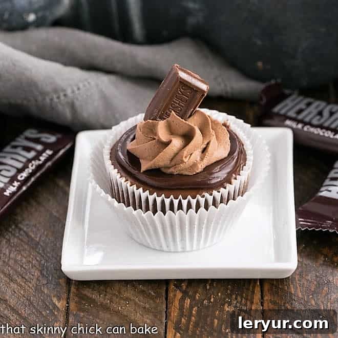 One perfectly portioned chocolate mini cheesecake on a square white plate, beautifully topped with a glossy chocolate ganache and a swirl of light chocolate whipped cream, ready to be enjoyed.