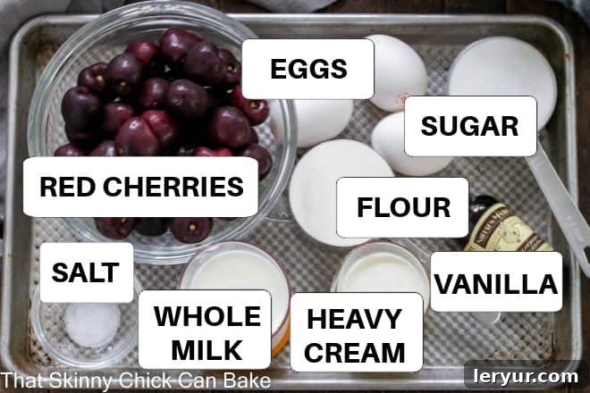 Rustic Whole Cherry Clafoutis 3 Various ingredients for cherry clafoutis laid out on a sheet pan with labels, including fresh cherries, eggs, sugar, flour, milk, and cream.
