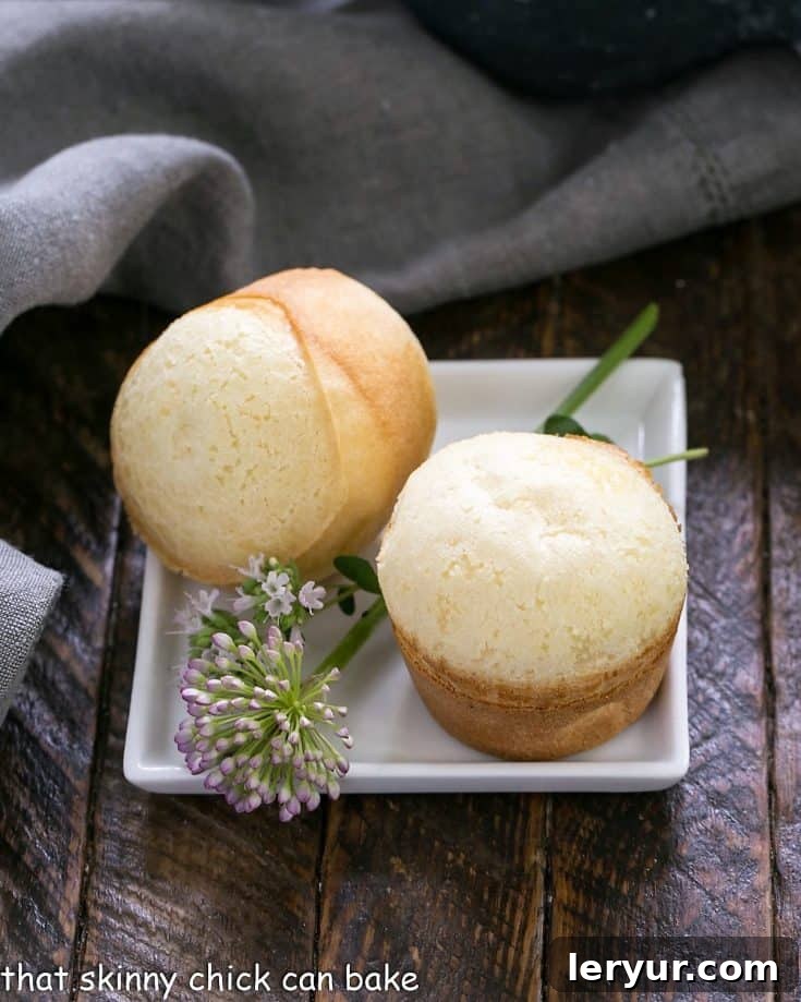 Two golden-brown Brazilian Cheese Breads served elegantly on a square white plate