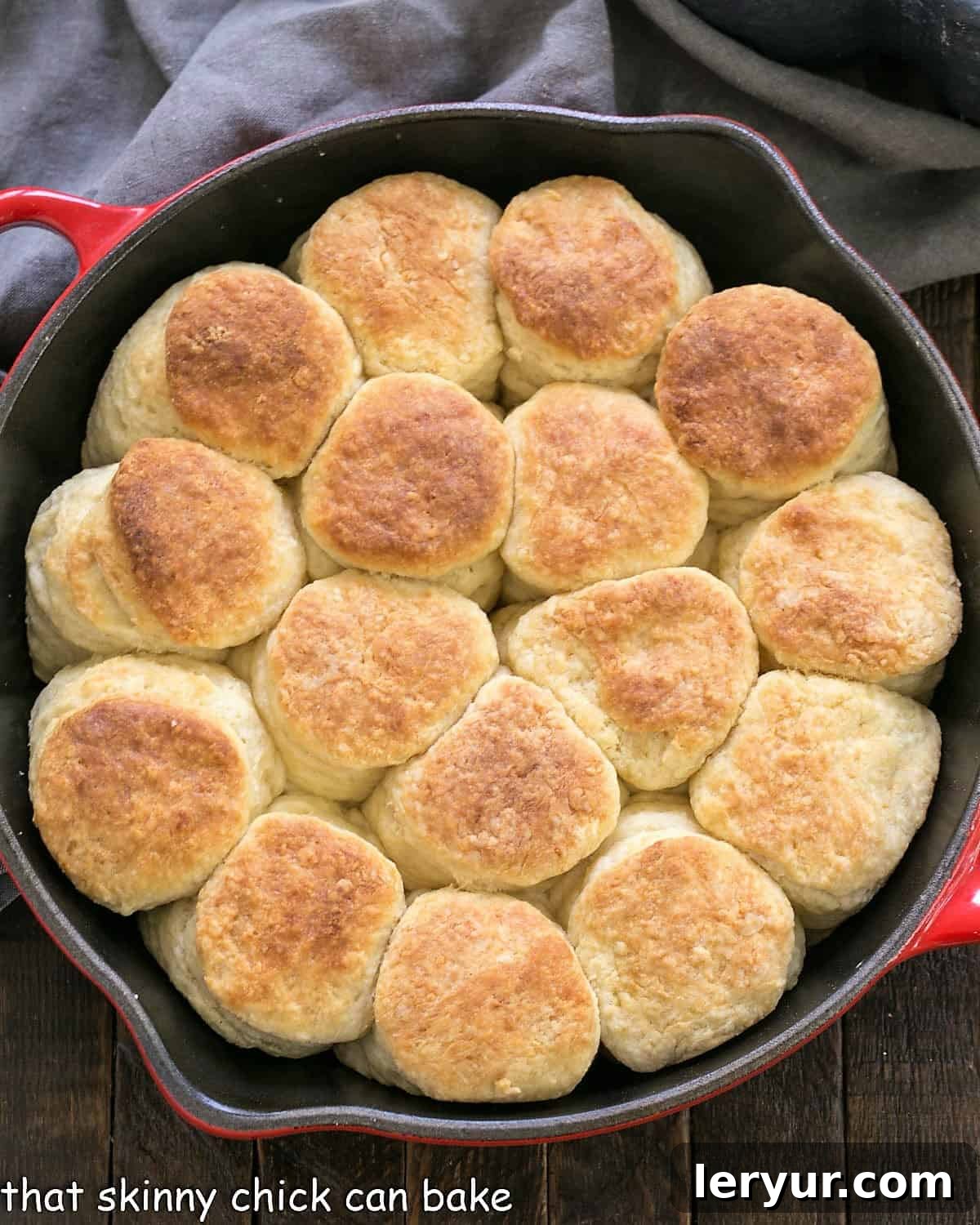 Overhead view of baked angel biscuits in a red cast iron skillet.