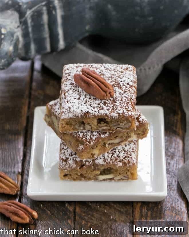 Three perfectly stacked Southern Pecan Bars on a square white plate, showing the dense, golden brown, and nutty layers.