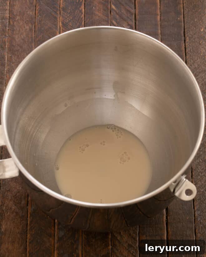 Activated yeast mixture carefully poured into the bowl of a stand mixer, ready for subsequent ingredients.