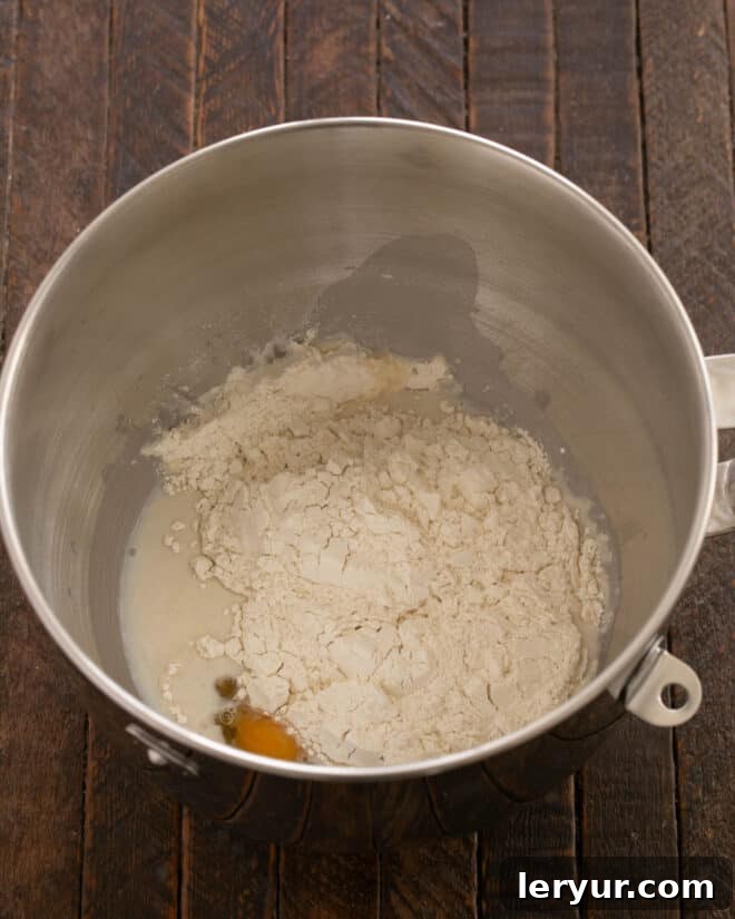 Remaining flour and salt being added to the dough mixture in the stand mixer.