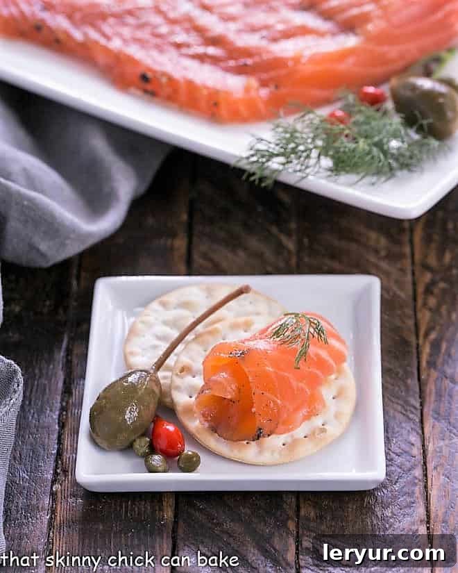 A delicate slice of gravlax adorned on a crisp cracker, presented on a pristine square white plate, ready for an elegant appetizer.