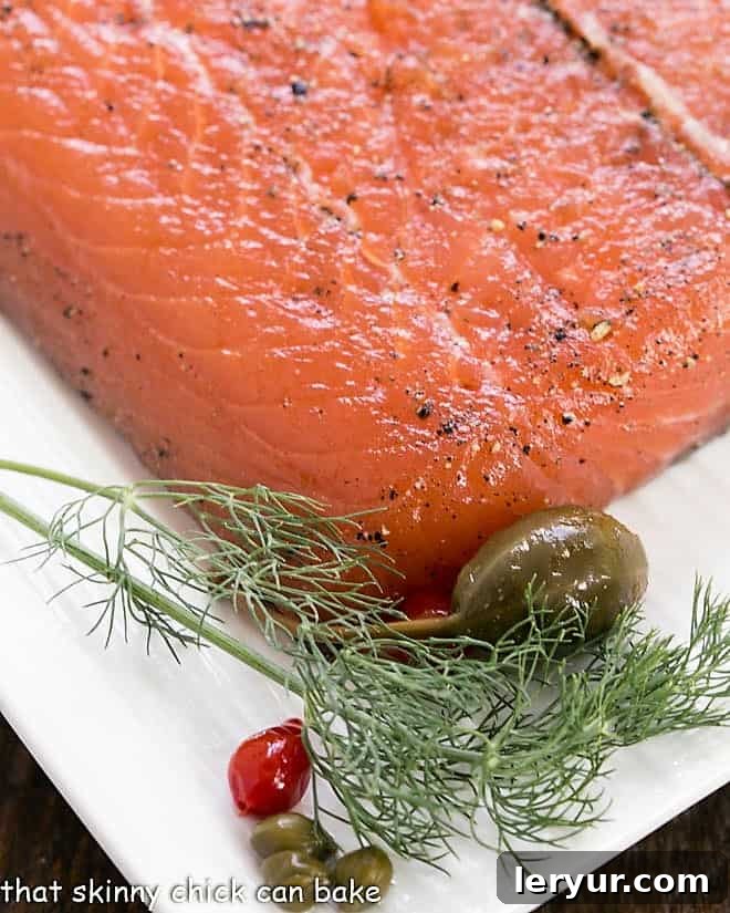 A close-up view of elegantly sliced gravlax arranged on a white platter, garnished with fresh dill for a touch of vibrant green.