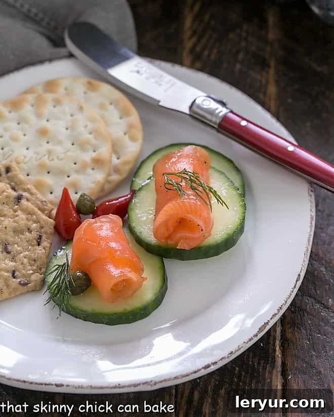 Delicate slices of gravlax elegantly arranged on crisp cucumber slices, presented on a pristine white appetizer plate, offering a refreshing and gourmet bite.