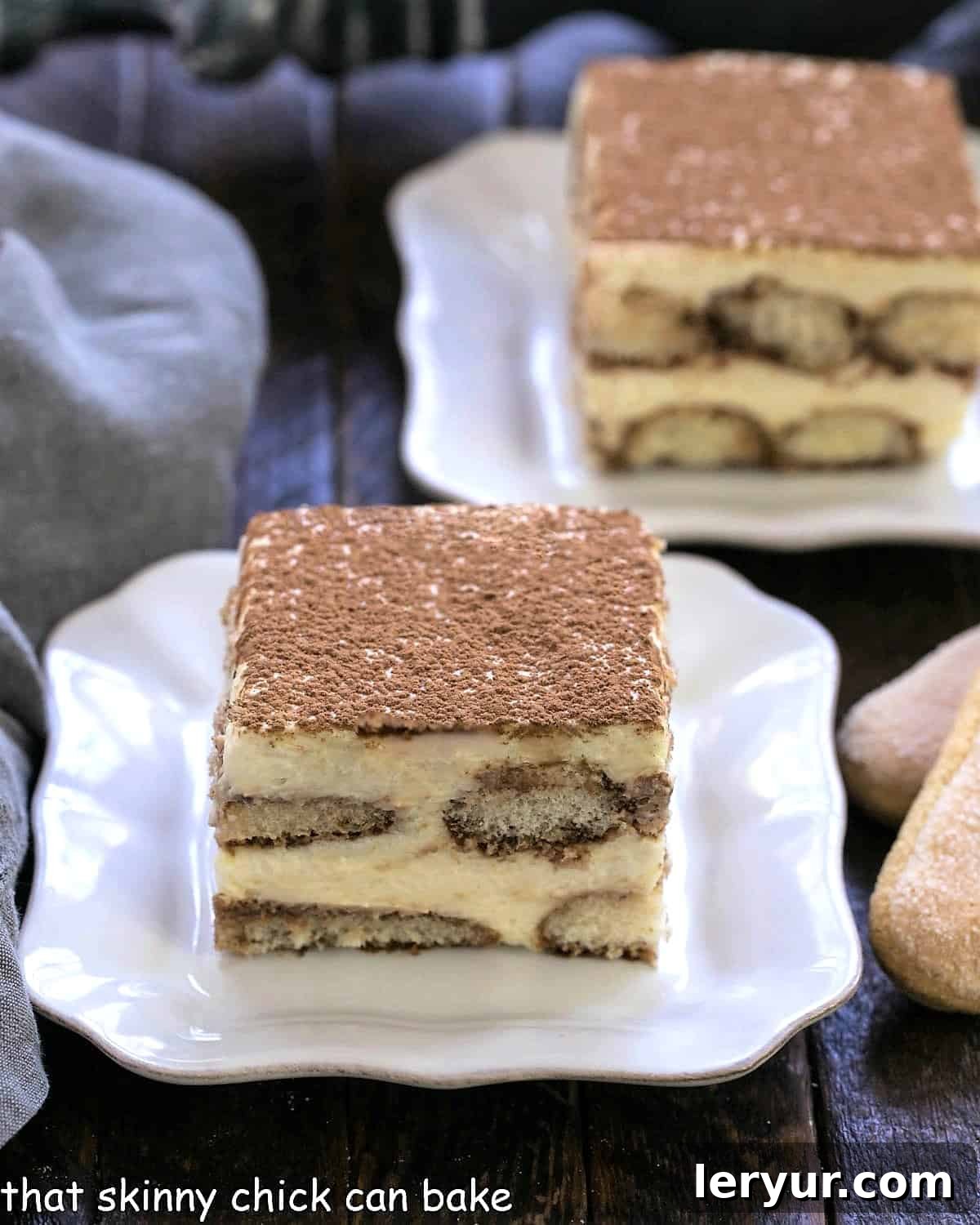 Decadent Tiramisu From Scratch 2 Two slices of tiramisu on square white plates with tips of 2 ladyfingers visible on the side.