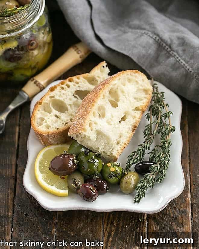 Herbed oives on a white plate with bread and fresh thyme