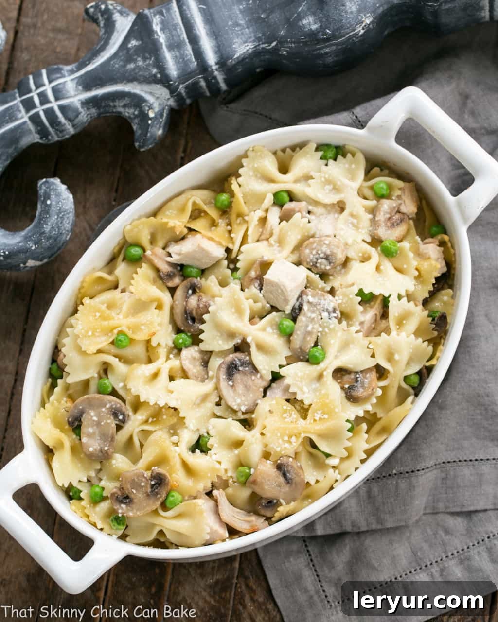 Classic Turkey Tetrazzini Recipe - The ultimate comfort food with leftover poultry, creamy sauce, tender pasta, peas, and savory mushrooms. A perfect post-Thanksgiving meal! Overhead view of a comforting turkey tetrazzini dish in an oval white casserole, ready to serve.