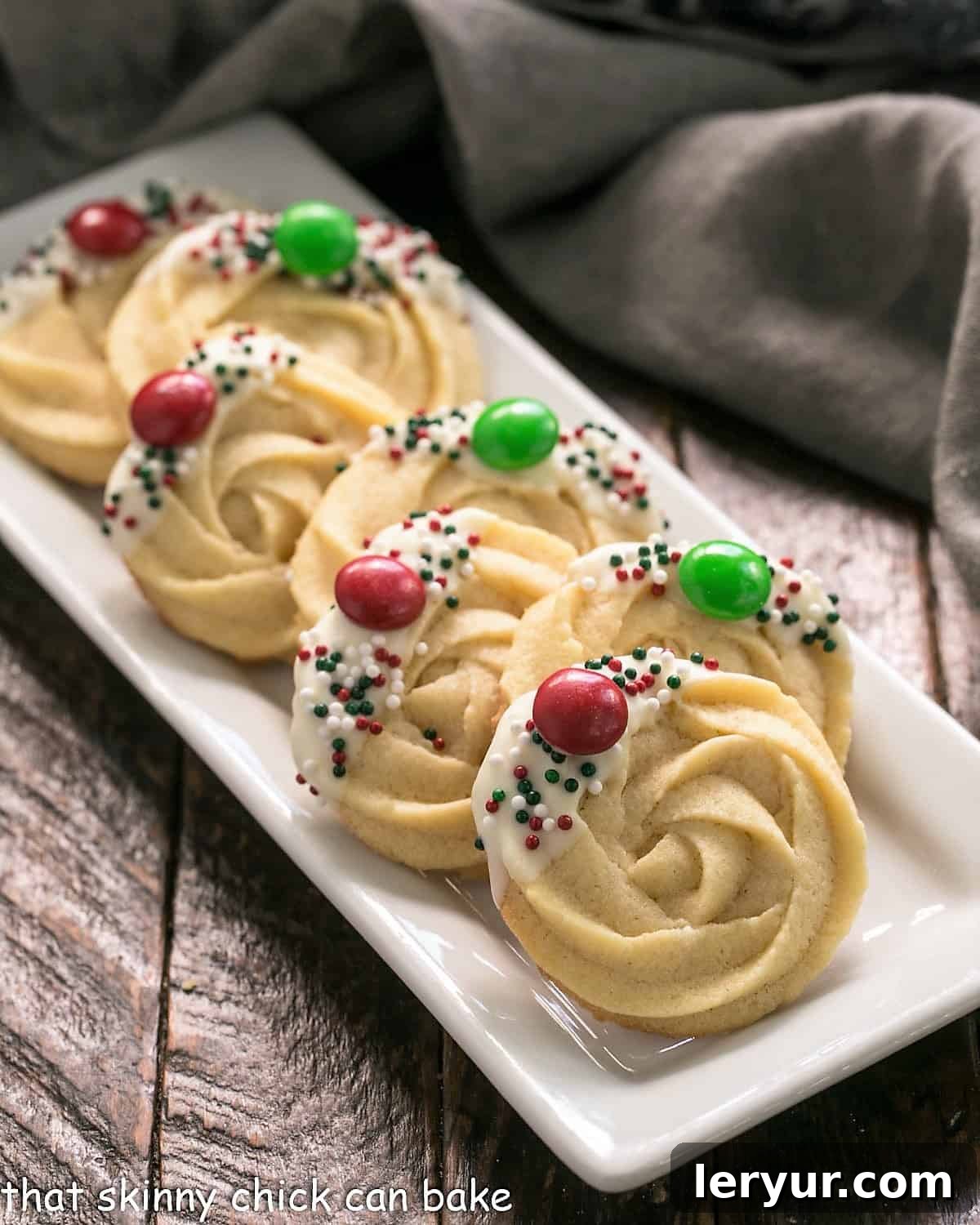 A vibrant selection of decorated Danish Butter cookies, featuring various chocolate dips and colorful sprinkles, arranged on a pristine white tray.