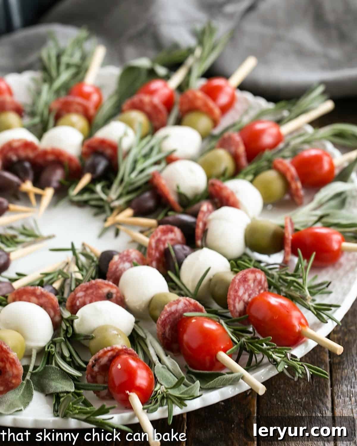Close-up view of vibrant Antipasto Wreath skewers on a pristine white round plate, garnished with fresh rosemary.